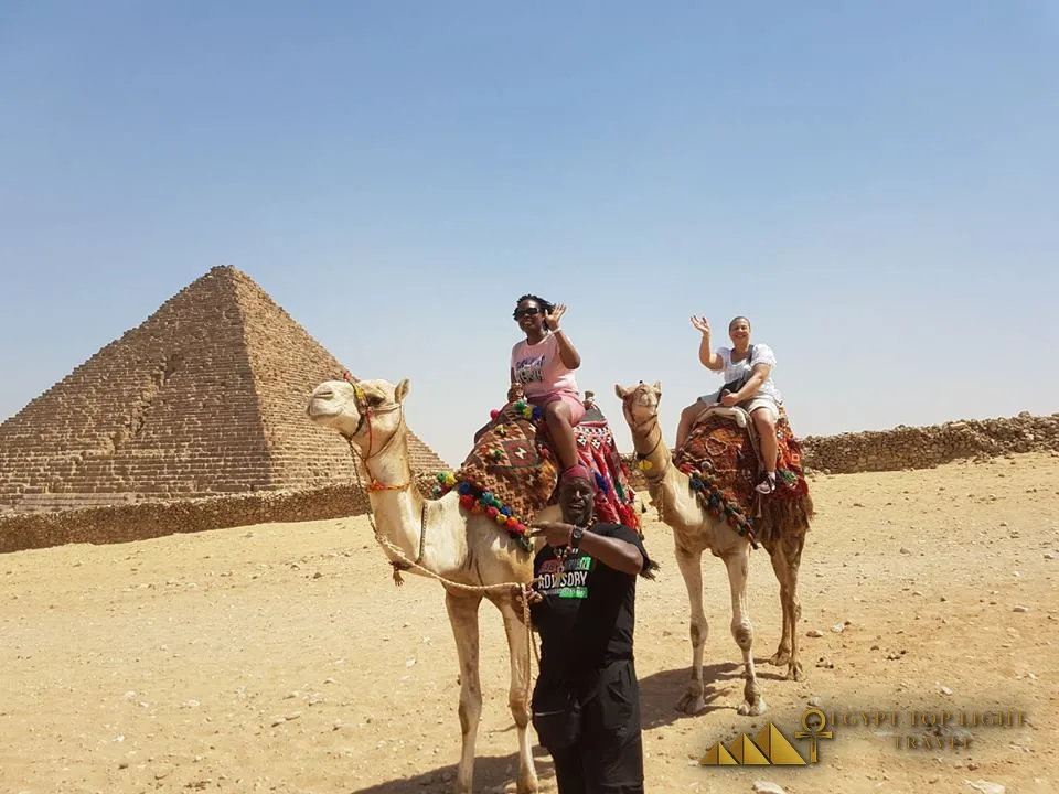 Travellers on camels before the Pyramids of Giza with their guide