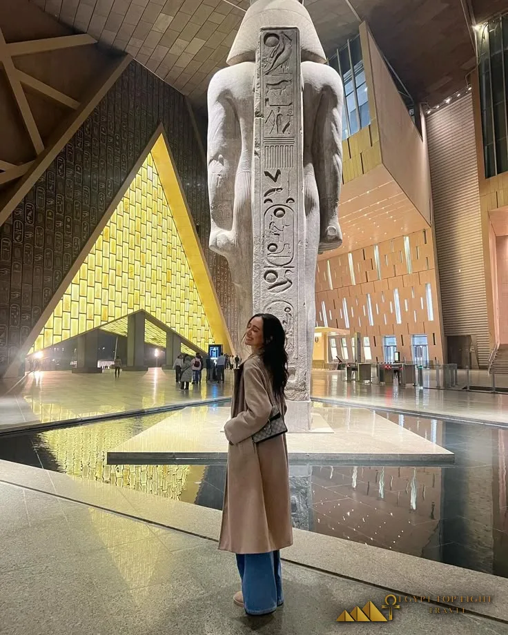 Traveler beside the colossal statue of Ramesses II at the Grand Egyptian Museum